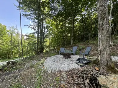 a campsite with two chairs and a campfire in the woods at Cabin Zoobox 79 in Eastman