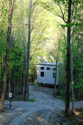 a small white building in the middle of a forest at Cabin Zoobox 55 in Eastman