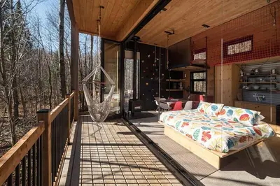 a porch with a bed and a hammock on a deck at Cabin Zoobox 56 in Eastman