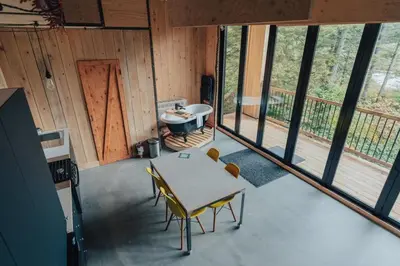 a room with a table and chairs and a tub at Cabin Zoobox 88 in Eastman