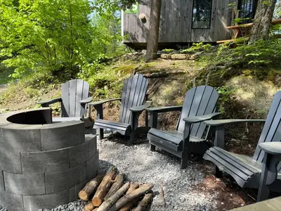 a group of chairs sitting next to a fire pit at Cabin Zoobox 65 in Eastman