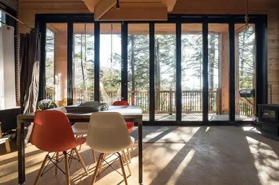 a dining room with a table and chairs and windows at Cabin Zoobox 67 in Eastman