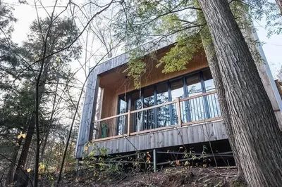 a house sitting on top of a hill next to a tree at Cabin Zoobox 68 in Eastman