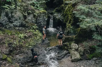 three people standing in a stream in a waterfall at Cabin Zoobox 82 in Eastman