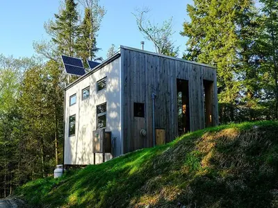 a house on top of a grassy hill at Cabin Zoobox 83 in Eastman