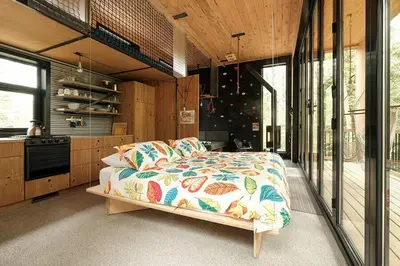 a bedroom with a bed and a kitchen with windows at Cabin Zoobox 83 in Eastman