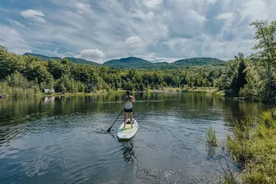 a woman on a paddle board on a river at Cabin Zoobox 84 in Eastman