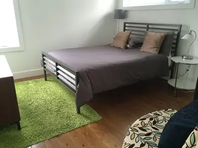 a bedroom with a large bed with a green rug at Cottage 35 Chemin Gilbert in Eastman