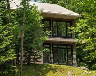 a house with large windows on top of a yard at Cottage 35 Chemin Gilbert in Eastman