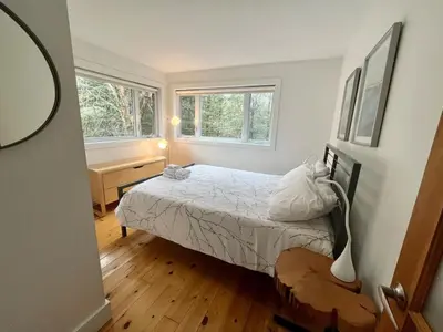 a small bedroom with a bed and two windows at Cottage 61 des Cervidés in Eastman