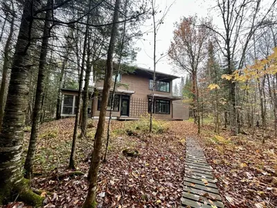 a house in the woods with a path in front of it at Cottage 61 des Cervidés in Eastman