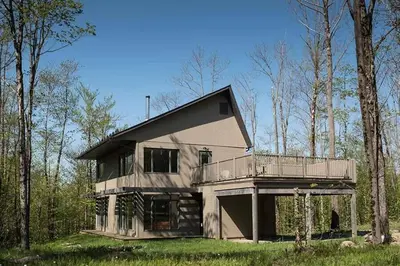 a large house with a balcony in the woods at Cottage 2 de la Chute in Eastman