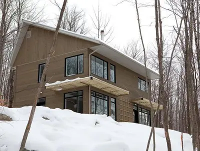 a house in the woods with snow in front of it at Cottage 2 de la Chute in Eastman