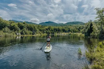 a woman on a paddle board on a river at Cottage 2 de la Chute in Eastman