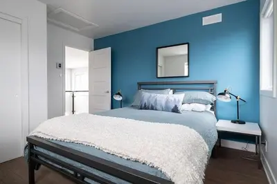 a blue bedroom with a large bed and a mirror at Cottage 2 de la Chute in Eastman