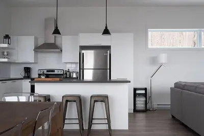 a kitchen with a bar with two stools and a counter top at Cottage 121 chemin Gilbert in Eastman