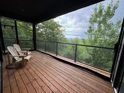 a screened in porch with two chairs on the deck at Cottage 121 chemin Gilbert in Eastman