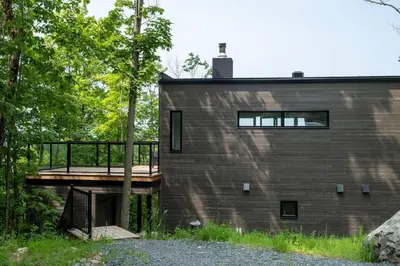a house with a wooden deck next to a building at Cottage 121 chemin Gilbert in Eastman