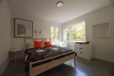 a bedroom with a bed with orange pillows and a window at Cottage 18 place de la Réserve in Eastman