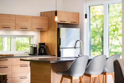 a kitchen with wooden cabinets and a stainless steel refrigerator at Cottage 18 place de la Réserve in Eastman
