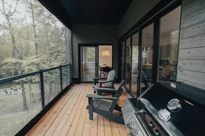 a screened in porch with a cat sitting in a chair at Cottage 42 de la Réserve in Eastman