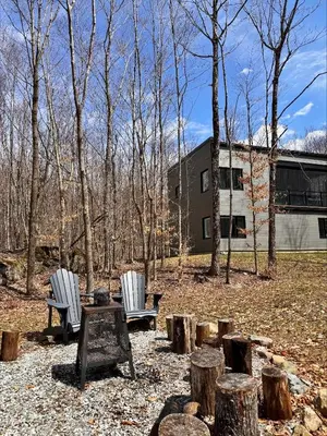 two chairs and a table in a yard with trees at Cottage 42 de la Réserve in Eastman