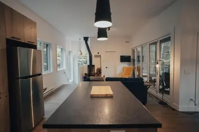 a kitchen and living room with a table and a refrigerator at Cottage 42 de la Réserve in Eastman