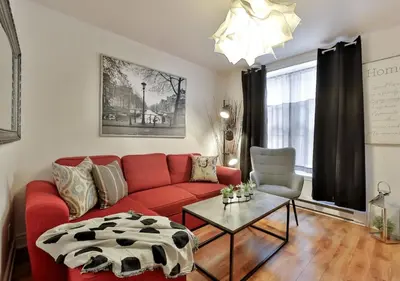a living room with a red couch and a table at 100 METERS to METRO BEAUDRY - FULL APARTMENTS - 1 minute walk to the FAMOUS ST CATHERINE STREET - FAST WIFI - WASHER & DRYER ON SITE - Montcalm units in Montréal