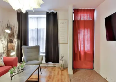 a living room with a red door and a chair at 100 METERS to METRO BEAUDRY - FULL APARTMENTS - 1 minute walk to the FAMOUS ST CATHERINE STREET - FAST WIFI - WASHER & DRYER ON SITE - Montcalm units in Montréal
