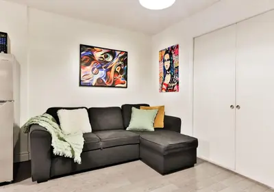 a living room with a couch and paintings on the wall at 100 METERS to METRO BEAUDRY - FULL APARTMENTS - 1 minute walk to the FAMOUS ST CATHERINE STREET - FAST WIFI - WASHER & DRYER ON SITE - Montcalm units in Montréal