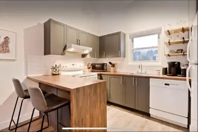 a kitchen with a wooden table and a sink at Cap Magog! Près du lac Memphrémagog et Mont Orford in Magog-Orford