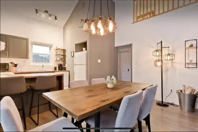 a kitchen and dining room with a wooden table and chairs at Cap Magog! Près du lac Memphrémagog et Mont Orford in Magog-Orford