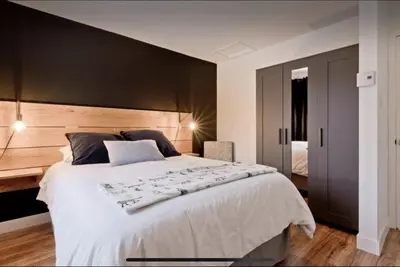 a bedroom with a large white bed with a black wall at Cap Magog! Près du lac Memphrémagog et Mont Orford in Magog-Orford