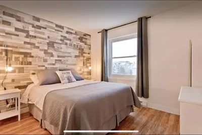 a bedroom with a bed and a brick wall at Cap Magog! Près du lac Memphrémagog et Mont Orford in Magog-Orford