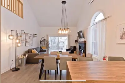 a dining room and living room with a table and chairs at Cap Magog! Près du lac Memphrémagog et Mont Orford in Magog-Orford