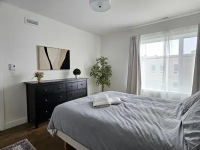 a bedroom with a bed and a dresser and a window at Le Mont-Royal Sky by HomeInMontreal in Montréal