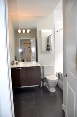a bathroom with a toilet and a sink and a mirror at Le Mont-Royal Sky by HomeInMontreal in Montréal
