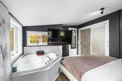 a bedroom with a bed and a bath tub and a television at Appart M1 avec bain tourbillon citq 309409 in Mascouche