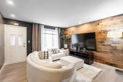 a living room with a white couch and a tv at Appart M1 avec bain tourbillon citq 309409 in Mascouche