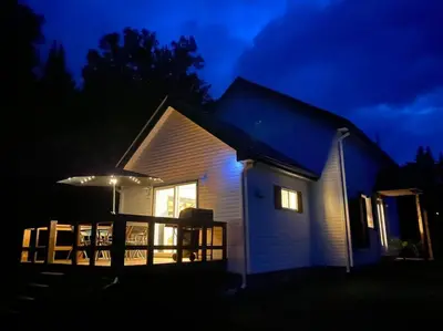 a small house with a porch at night at LE JAZZ- Chalet rustique/chic avec SPA in Notre-Dame-Des-Bois