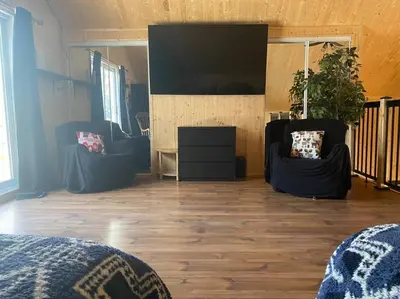 a living room with two chairs and a flat screen tv at LE JAZZ- Chalet rustique/chic avec SPA in Notre-Dame-Des-Bois