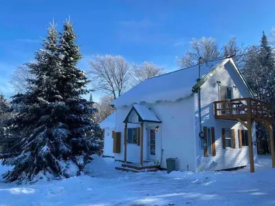 a white house with a christmas tree in the snow at LE JAZZ- Chalet rustique/chic avec SPA in Notre-Dame-Des-Bois