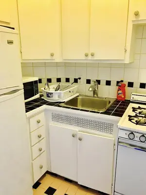 a kitchen with white cabinets and a sink at Stylish Montreal Apartment: Comfortable Stay in the Golden Square Mile in Montréal
