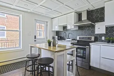 a kitchen with white cabinets and bar stools at Downtown Prestige: Parking, King Bed, Sleeps 6 in Sherbrooke