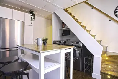a kitchen with a white counter and a staircase at Downtown Prestige: Parking, King Bed, Sleeps 6 in Sherbrooke