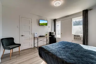 a bedroom with a bed and a chair and a television at Motel Saint Bruno in Saint-Bruno-de-Montarville