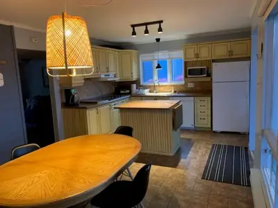 a kitchen with a wooden table and a kitchen with white appliances at Chalet de Mimi in Coaticook