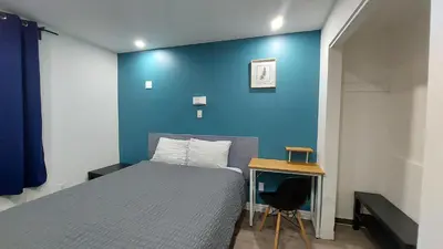 a bedroom with a blue wall with a bed and a desk at APD HOTEL in Montréal