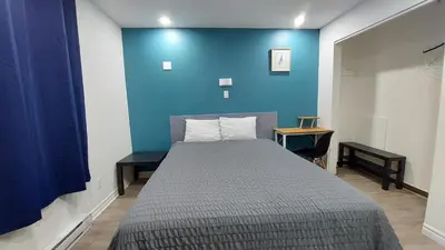 a bedroom with a bed with a blue wall at APD HOTEL in Montréal