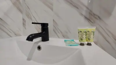 a bathroom sink with a black faucet and a cup at APD HOTEL in Montréal